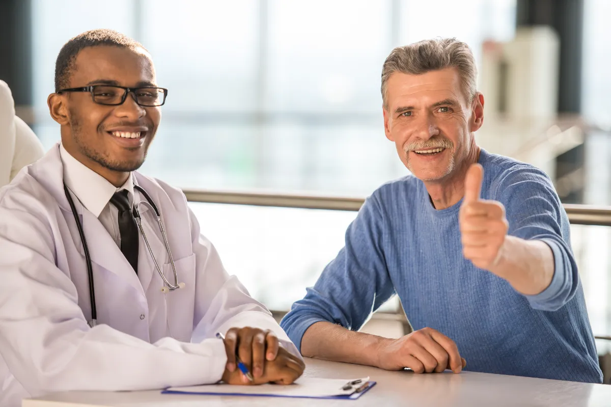 Patient sat next to doctor doing a thumbs up